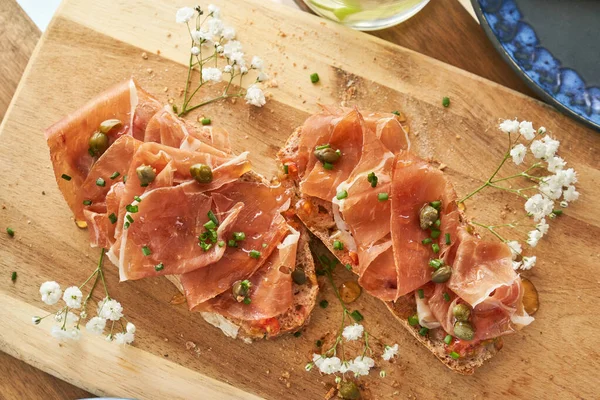 Top View Delicious Bruschettas Prosciutto Capers Served Wooden Cutting Board — Stock Photo, Image