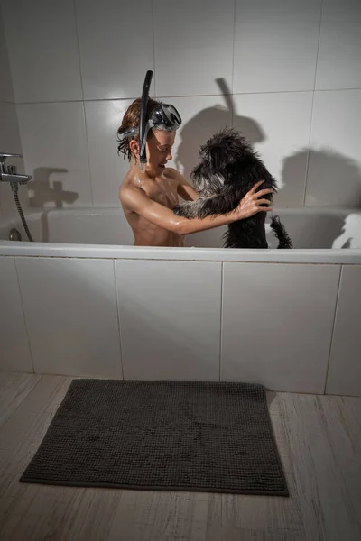 Вид Сбоку Мальчика Водолазной Маске Играющего Черной Собакой Сидя Ванне — стоковое фото