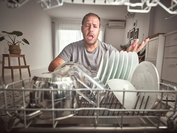 Недовольство Мужчины Повседневной Одежде Сидя Рядом Современной Открытой Посудомоечной Машиной — стоковое фото