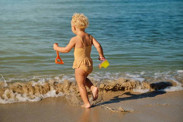 Zadní Pohled Malé Blond Kudrnaté Dítě Žlutých Plavkách Moře Písečné — Stock fotografie