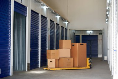 Endüstriyel bir binada, geri dönüşümlü karton kutuları palet rafının üstünde olan girişimcilere ya da kişilere kiralanacak bir depo.