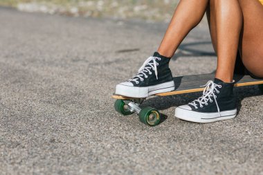 Bulutlu gökyüzünün altındaki tepeler arasında asfalt yolda duran tanınmayan genç bir kadın.