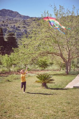 Gün ortasında güneşten kavrulmuş arazide uçurtma için koşan bir çocuk vücudu.