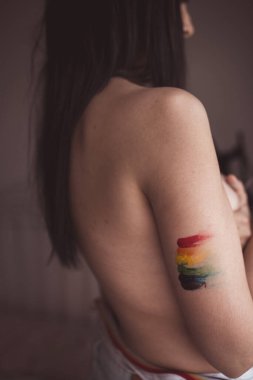 Göğüsleri örten ve LGBT sembolü çizen çekici çıplak kadın.