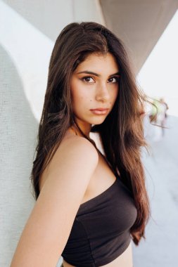 Güzel kadın duvarın yanında duruyor.