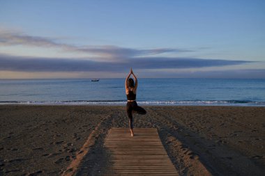Kumlu sahilde yoga eğitimi sırasında isimsiz bir kadının namaste elleriyle yaptığı poz.