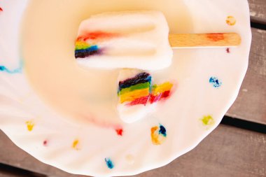Süslü tabakta LGBT sembolü olan tahta çubukta dondurma.