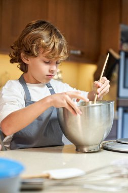Stock vertical photo of a child mixing ingredients in a metal container clipart