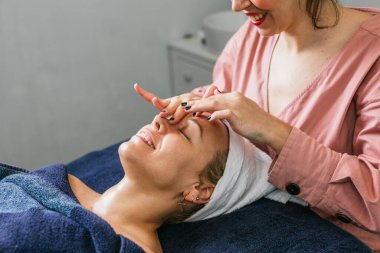 Güzellik salonunda masanın üzerinde yatan bayan müşterinin omuzlarına masaj yapan tanınmamış bir masöz.