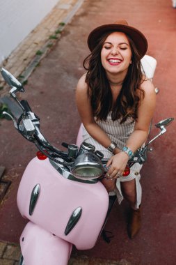 Caddedeki pembe motosiklette gözleri kapalı, büyüleyici, gülümseyen bir kadından.