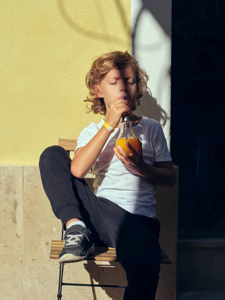 Leuke Jongen Drinken Vers Sap Uit Glazen Fles Terwijl Zitten — Stockfoto