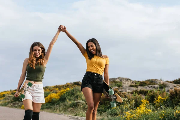 Onnellinen Monikansallinen Tyttöystäviä Kädestä Kävellessään Tiellä Longboards — kuvapankkivalokuva