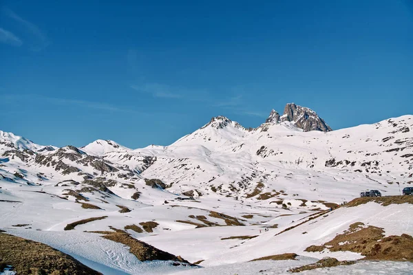 青い雲のない空の下に位置する白い雪で覆われた荒い岩の丘の壮観な風景 — ストック写真
