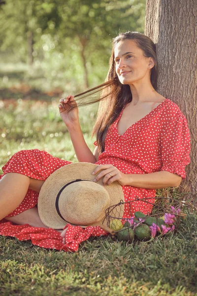 Charming Young Female Red Dress Straw Hat Sitting Grass — Stock Photo, Image