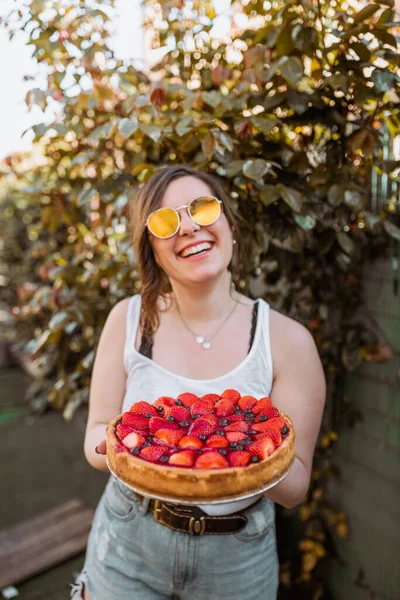 一个快乐的女人拿着一个美味的草莓蛋糕 — 图库照片