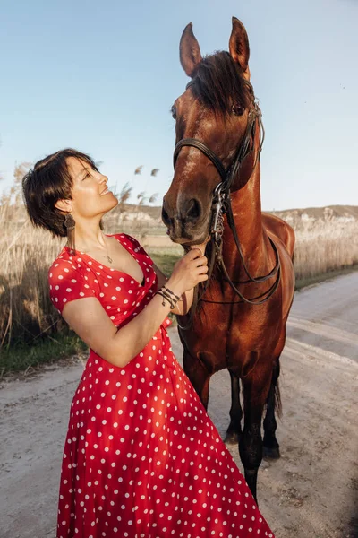 Νεαρή Γυναίκα Μακρύ Κόκκινο Φόρεμα Κοιτάζοντας Άλογο Ενώ Στέκεται Στην — Φωτογραφία Αρχείου