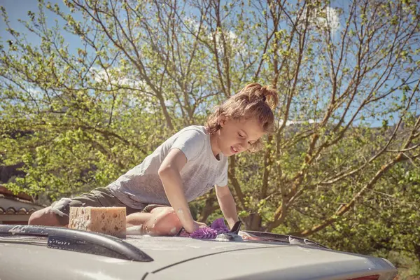 Skupiony Nastolatek Gąbką Myjący Dach Nowoczesnego Samochodu Zaparkowanego Naturze Słoneczny — Zdjęcie stockowe