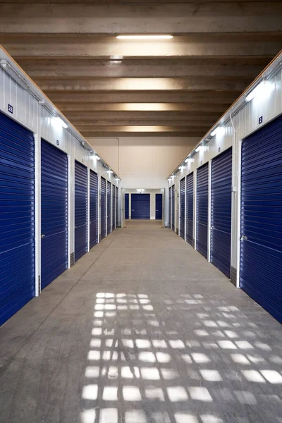 stock image Long narrow corridor with storage with blue shutter automatic doors in an industrial building for rental to entrepreneurs or individuals