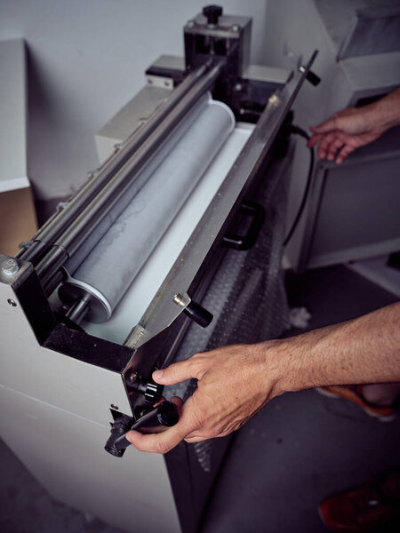 Crop unrecognizable male worker checking machine while using electric tool during work process