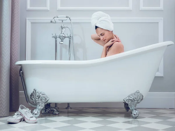 머리에 수건과 욕조에 가벼운 욕실에서 어깨를 만지는 감각적인 여성의 — 스톡 사진