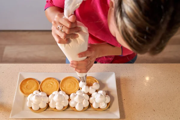 Anonim kadın pasta şefinin, boru torbasıyla tartlarda krema yaparken en iyi görüntüsü.