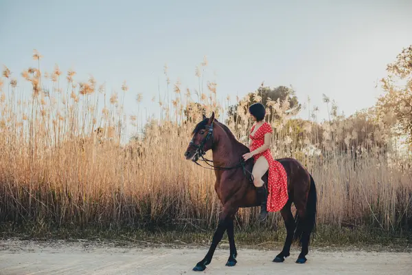Молодая Женщина Красном Платье Сидя Лошади Сельской Дороге Возле Поля — стоковое фото