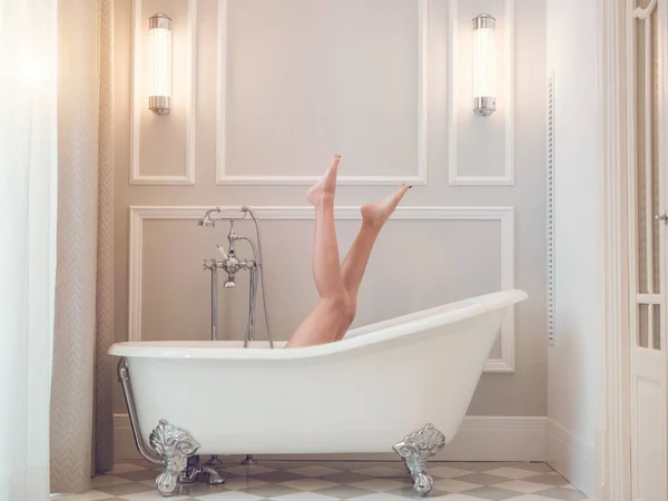 在酒店浴室里躺在白色浴缸里 双腿凸起的无法辨认的赤脚女性侧视图 — 图库照片