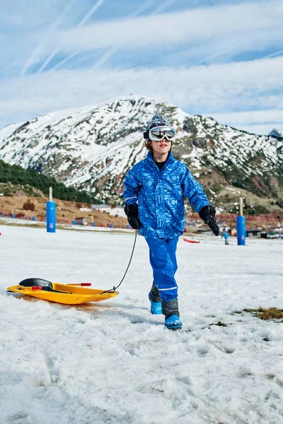 Kind Oberbekleidung Mit Gelbem Schlitten Läuft Auf Schnee Gegen Berggipfel — Stockfoto