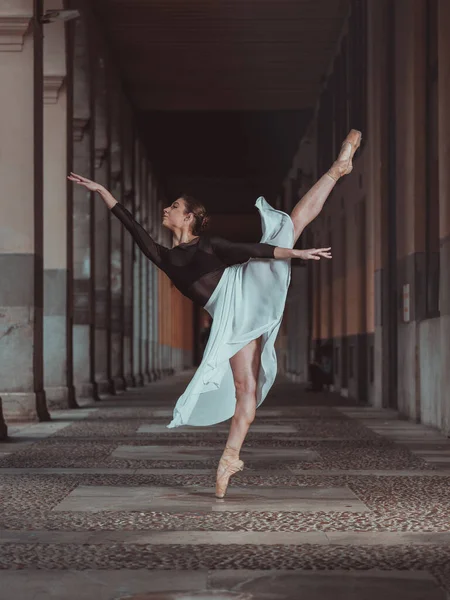 满身优雅的芭蕾舞演员穿着丝裙 脚尖的鞋子 在空旷的楼道上 以阿拉伯式的芭蕾舞姿势保持平衡 — 图库照片