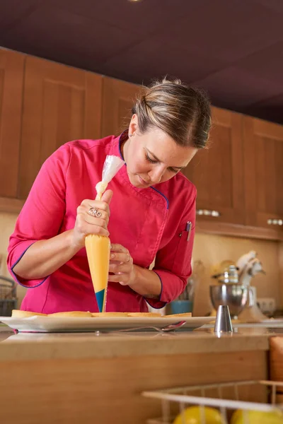Kadın Pasta Şefi Fırınının Mutfağında Dururken Turtaların Üstünde Krema Yapıyor — Stok fotoğraf