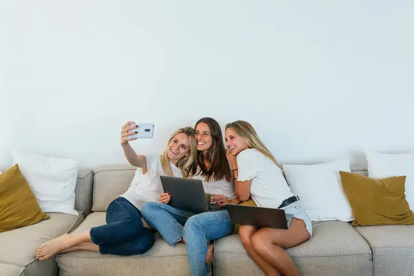 Žena Selfie Mobilem Veselým Ženským Kamarádkám Sedícím Gauči Obýváku — Stock fotografie