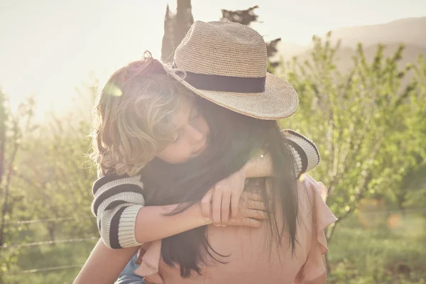 晴れた夏の日に緑色の牧草地で休む息子と帽子で若い女性のバックビュー — ストック写真
