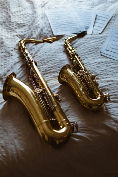 Вышесказанного Саксофоны Листы Напечатанной Музыки Помещены Белом Белье Кровати — стоковое фото