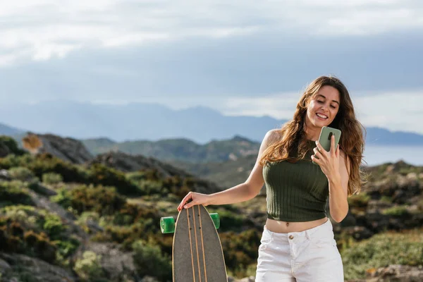 Χαμογελώντας Θηλυκό Skateboarder Longboard Μήνυμα Κειμένου Στο Κινητό Τηλέφωνο Κατά — Φωτογραφία Αρχείου
