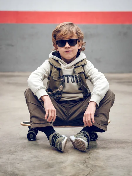 Ganzkörper Ernster Junge Stylischer Kleidung Und Sonnenbrille Sitzt Auf Skateboard — Stockfoto