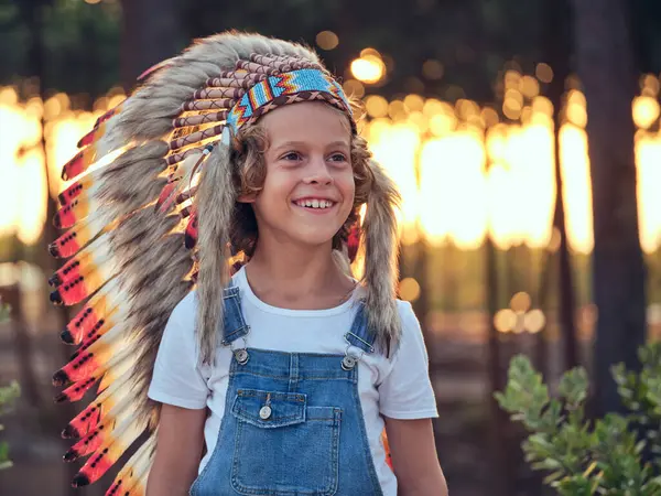 一个快乐的男孩 头戴真实的美国本土头饰 头戴五颜六色的羽毛 站在乡间 背景模糊 — 图库照片