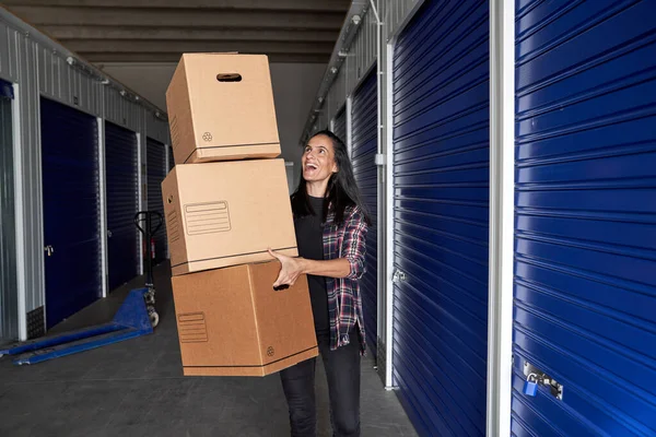 Pozitif kadın, taşınma günü boyunca kişisel eşyalarıyla dolu karton kutuları taşırken yukarı bakıyor.