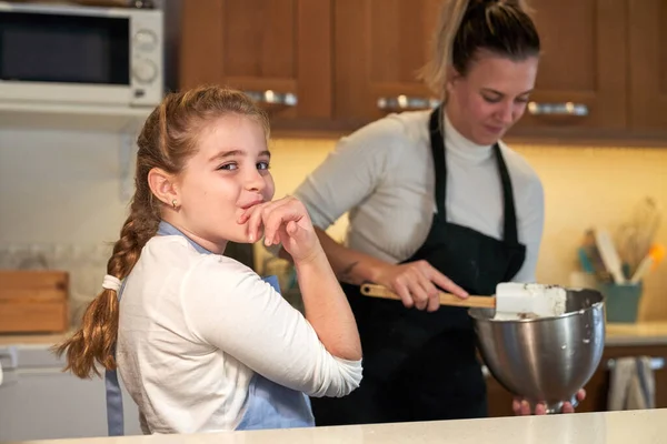 Zdjęcie Dziewczyny Fartuchu Liżącej Rękę Kuchni Dziewczyną Tle Mieszającą Składniki — Zdjęcie stockowe