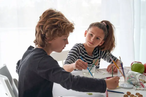 Crianças Adoráveis Pintando Papel Com Pincéis Enquanto Sentam Juntos Mesa — Fotografia de Stock
