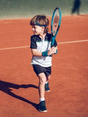 Sıkı kortta tenis oynarken spor giyim kuşamında raketle felce hazırlanan sevimli çocuk vücudu.