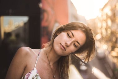 Uzun saçlı, yaz elbisesi giymiş, arka planda bulanık bakışlı çekici manken.