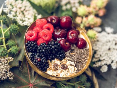 Yoğurtlu, tohumlu ve müsli karışımlı lezzetli kahvaltı kasesinden taze meyveli ve çiçekli.