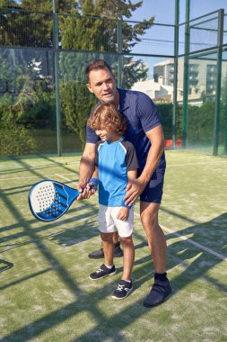 Yaz günü spor sahasında Padel antrenmanı sırasında topa raketle vurmayı öğreten antrenörle dolu bir vücut.