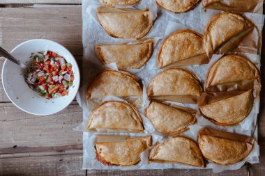 Fırın tepsisiyle taze pişmiş turtalar köfte kasenin yanında altın çıtır ekmek ve soğan.