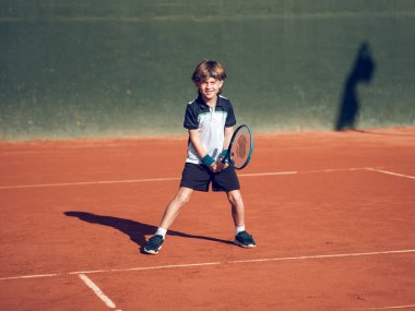 Güneşli bir günde sahada tenis oynarken spor giyim ve spor ayakkabılarında raket tutan bir sürü pozitif sporcu çocuk.
