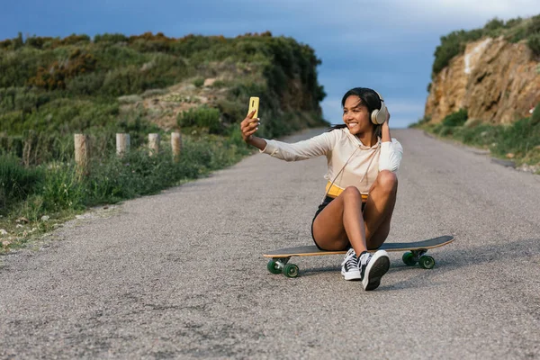 Εθνοτική Γυναικεία Λήψη Selfie Smartphone Ενώ Κάθεται Longboard Άσφαλτο Δρόμο — Φωτογραφία Αρχείου