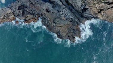 İspanya, Cantabria 'da mavi gökyüzünün altında kayalık kaya manzarası ve dalgalanan turkuaz deniz manzarası