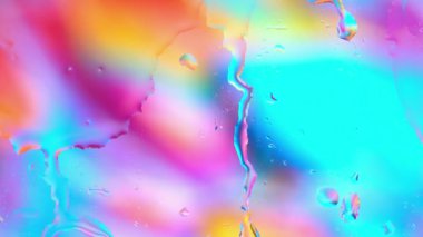 Renkli su penceresinden çok renkli arka planda yağmur damlalarıyla birlikte cam yüzeyine yayılıyor.