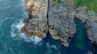 İspanya, Cantabria 'da mavi gökyüzünün altında kayalık kaya manzarası ve dalgalanan turkuaz deniz manzarası