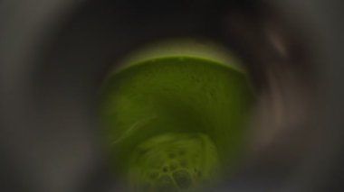 Yakın çekim yüksek açı gerçek zamanlı ekin anonim aşçı yeşil sebzeli meyve püresi ile karıştırıcının kapağını kaldırıyor.